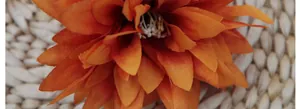 Macro close-up of orange artificial dahlia petals with realistic yellow stamens detail