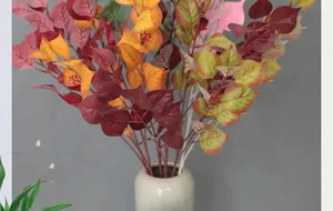 Autumnal faux leaf arrangement in a ceramic vase with vibrant red and orange foliage