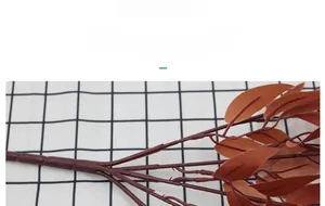 Detailed macro view of realistic faux willow branch with deep red lanceolate leaves