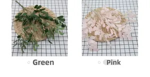 Detail of artificial peanut leaves in green and pink on a woven straw mat