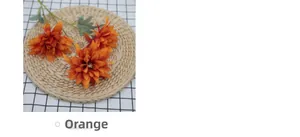 Detailed top view of 3-head orange dahlia artificial flowers on a rustic woven mat