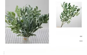 Close-up of artificial peanut leaves in a white woven vase with yellow ribbon