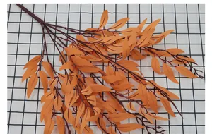 Macro shot of artificial autumn willow leaves with detailed orange texture on a plaid table