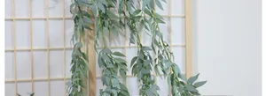 Detailed view of artificial green willow vine leaves hanging on a wooden screen