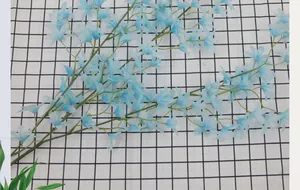 Close-up of artificial blue Oncidium orchid spray with lifelike silk petals on grid background