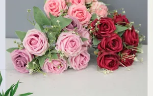Detalle de los pétalos de rosa de seda en rosa y rojo con hojas verdes y relleno floral