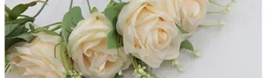 Detalle de rosas de seda color crema con pétalos densos y hojas verdes realistas