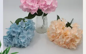 Detailed view of pink, blue and orange artificial hydrangea bouquets in a glass vase