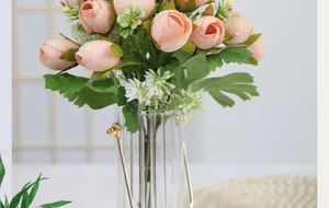 Pink artificial tea rose bouquet in a fluted glass vase with golden handle