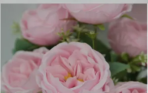Close-up of artificial pink Austin roses with delicate petals and green leaves for decor