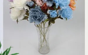 Detail of silk peony bouquet in blue and pink tones within a textured glass vase