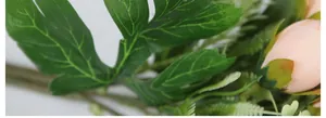 Macro shot of artificial tea rose buds and green leaves with realistic silk textures
