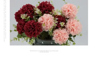 Detailed close-up of dark red and pink faux dahlia flowers in a ceramic vase