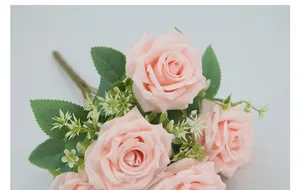Close-up of artificial pink roses with silk fabric petals and green leaves detail