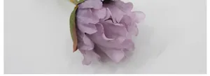 Macro shot of purple artificial silk peony petals with realistic textures and green sepals
