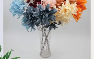 Detalle de arreglo de dalias y orquídeas de seda en un jarrón de vidrio transparente