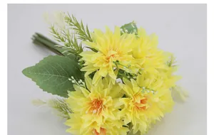 Macro view of artificial yellow African daisies with detailed silk petals and green leaves