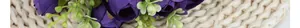 Close-up of artificial purple tea roses with green buds on beige woven texture