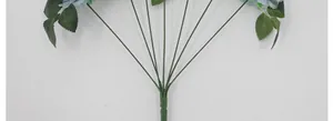 Detail van de lichtblauwe kunstbloemstelen en gekartelde groene bladeren op witte basis