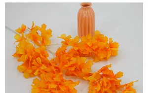 Primer plano de flores de cerezo de seda naranja y amarillo en jarrón de cerámica rosa