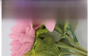 Close-up of pink artificial sunflower with detailed fabric petals and green leaves