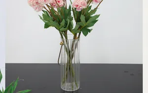 Macro-opname van een roze pompon-chrysant in een gestreepte glazen vaas met metalen handvat