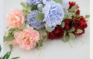Close-up of colorful artificial peony bouquet in pink, blue and red with green leaves