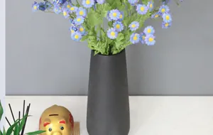 Detail von blauen Kunstmargeriten in einer schwarzen matten Keramikvase für Wohndeko