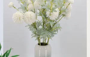 Detail of a white faux dandelion bouquet in a minimalist gradient ceramic vase