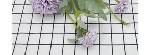 Top close-up view of purple artificial dandelion ball flower on black and white grid fabric