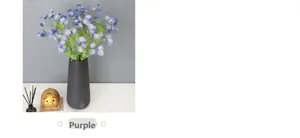 Purple artificial daisy bouquet in matte black vase with gold piggy bank decor