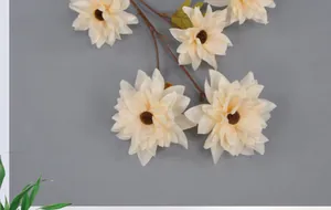 Macro view of creamy white faux dahlia blossoms with dark stamens on brown branches