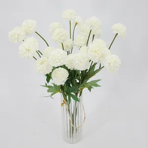 Witte kunstmatige pompon chrysanten in een verticaal geribbelde glazen vaas