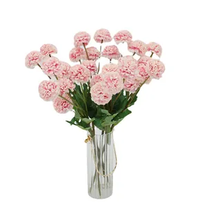 Roze kunstmatige paardenbloemen in een geribbelde glazen vaas met goudkleurig handvat