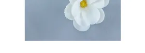 Close-up of white artificial magnolia flower with detailed yellow stamens on blue background