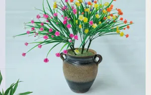 Detalle de flores de eucalipto artificiales de colores en una maceta de cerámica marrón
