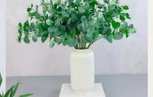Artificial eucalyptus leaves in white ceramic vase for minimalist home decor