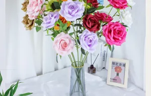 Detailed view of colorful artificial silk roses in a blue glass vase with leaf accents