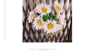Artificial pink sunflowers in a woven wall basket hanging on a rustic wooden trellis
