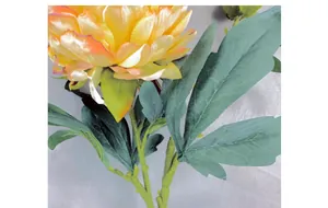 Close-up of yellow silk peony with burnt edges and detailed green leaves for home decor