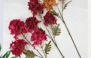 Detailed top view of artificial burgundy and orange hydrangeas on white fabric