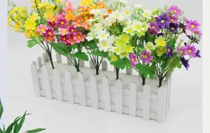 Detailed view of colorful artificial daisy bouquet in a white wooden fence planter box