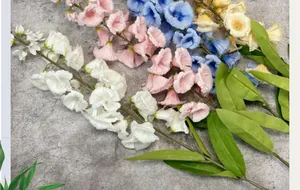 Close-up of silk lily of the valley flowers in four colors on a textured grey background