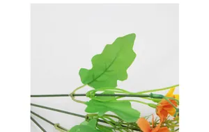 Macro shot of faux silk dancing orchid with vibrant orange petals and green serrated leaves