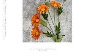 Macro shot of artificial orange daisies with realistic petals and green leaves on stone