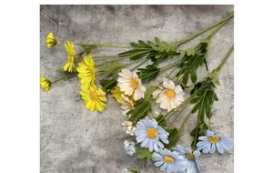 Flat lay of artificial daisy bouquets in yellow white and blue on a grey background