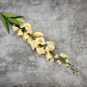 Artificial cream lily of the valley branch with green leaves on grey texture background