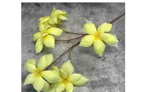 Detail of faux magnolia branch with soft yellow petals and realistic wood-textured stems