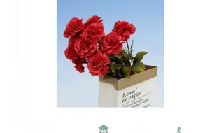 Close-up of deep red artificial carnations in a stylish white French paper bag vase