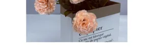 Detailed close-up of 13-head artificial pink carnations in a decorative paper bag